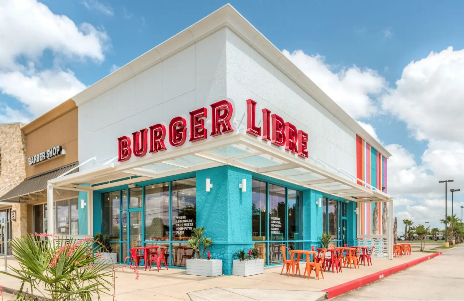 Burger Libre restaurant exterior in La Porte, TX designed by Texas Asbuilts, featuring bold red marquee signage, a turquoise storefront, white cantilevered canopy, and outdoor patio dining with red and orange café tables