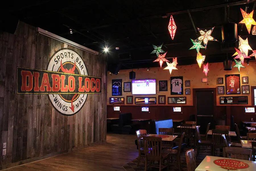 Diablo Loco sports bar interior with reclaimed wood walls, the Diablo Loco logo mural, and colorful star pendant lights