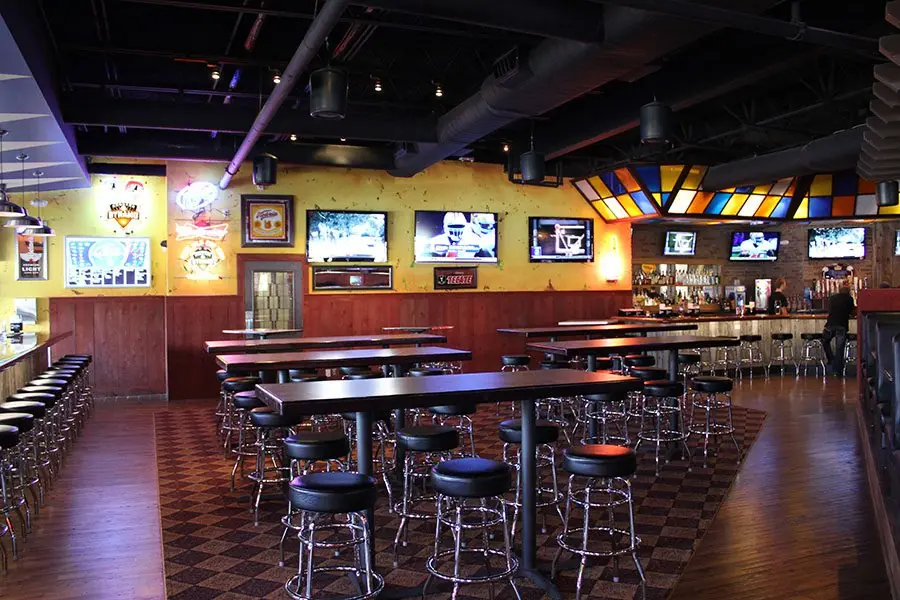 Diablo Loco main dining and bar room with high-top tables, multiple TVs, and a stained-glass ceiling feature over the bar