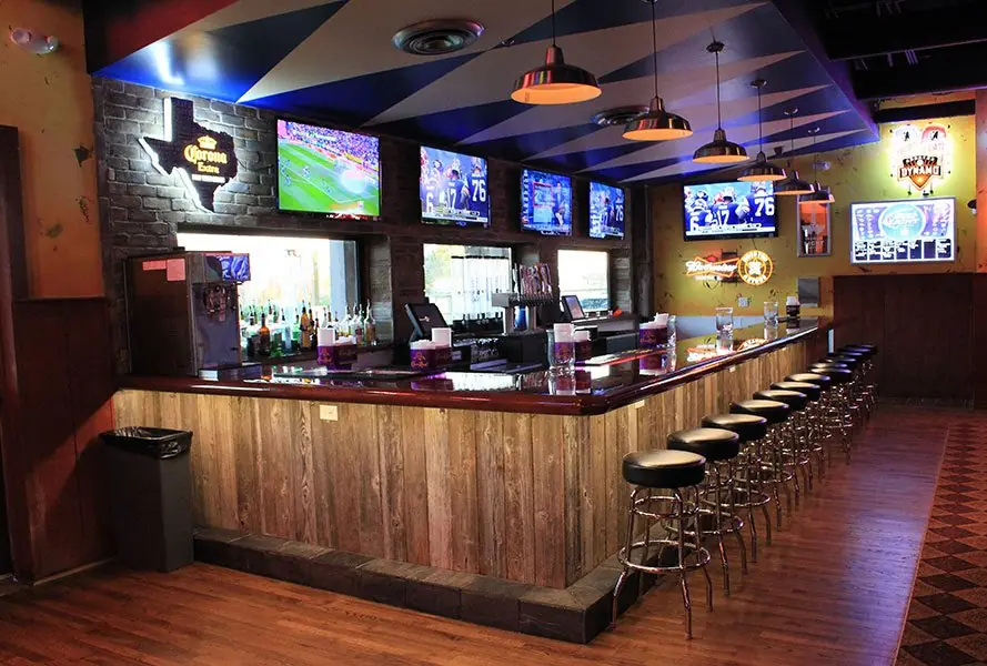 Long bar at Diablo Loco with multiple TVs, a Texas-shaped Corona sign, and a wood-paneled bar front