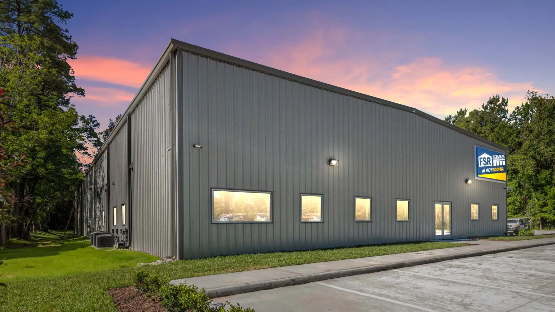 Exterior of FSR Services headquarters in Humble, TX at dusk, a pre-engineered metal building with gray standing seam walls and branded signage