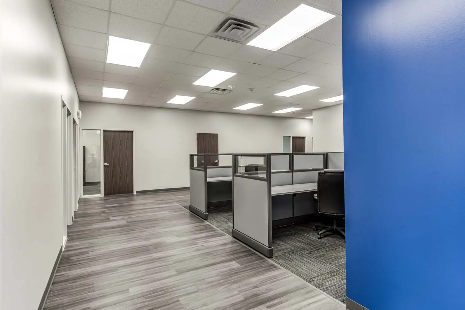 Open office area at FSR Services with workstations, glass-topped cubicle panels, and a blue feature wall