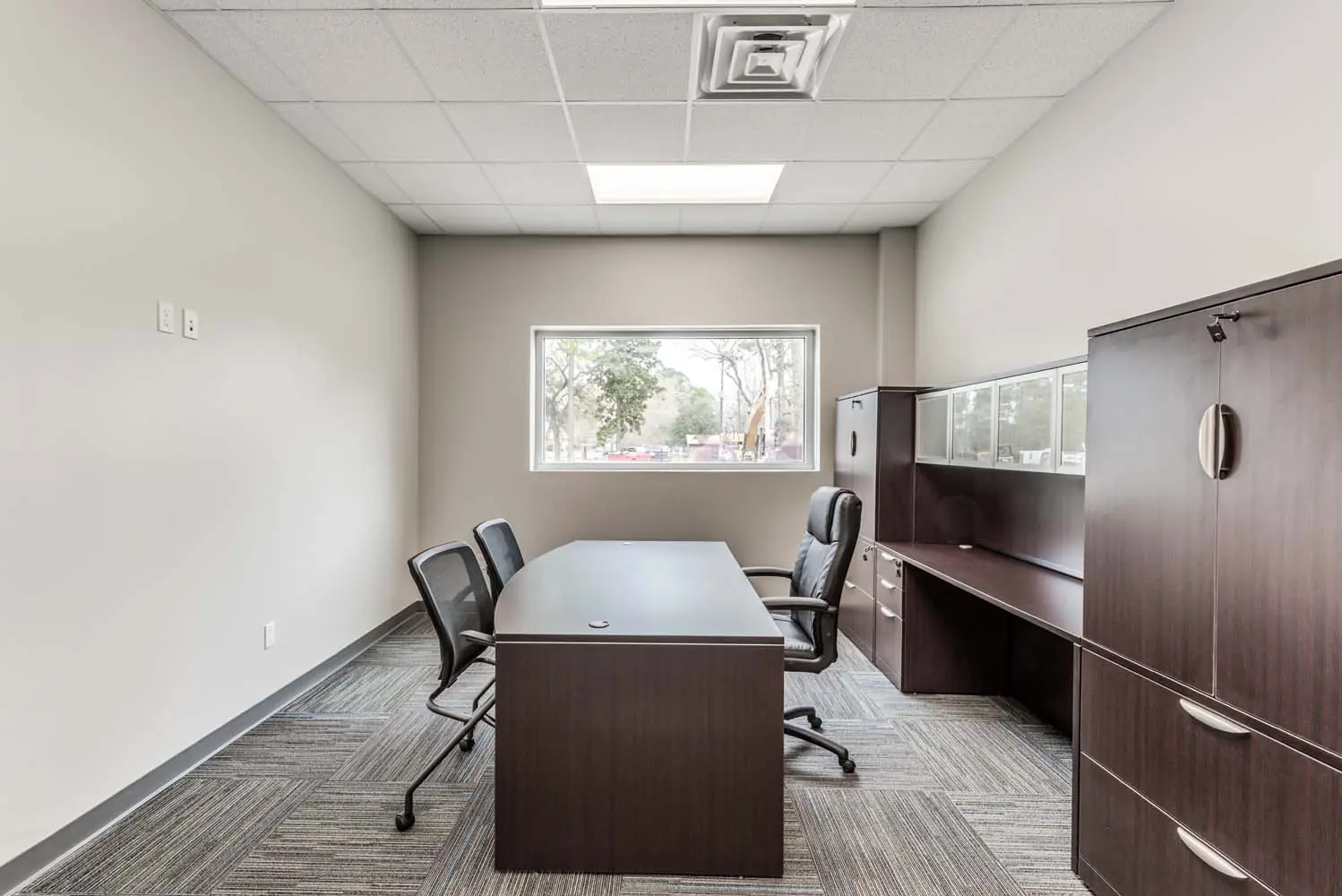 Executive office at FSR Services with dark wood desk and credenza, framed by a wide window with exterior view