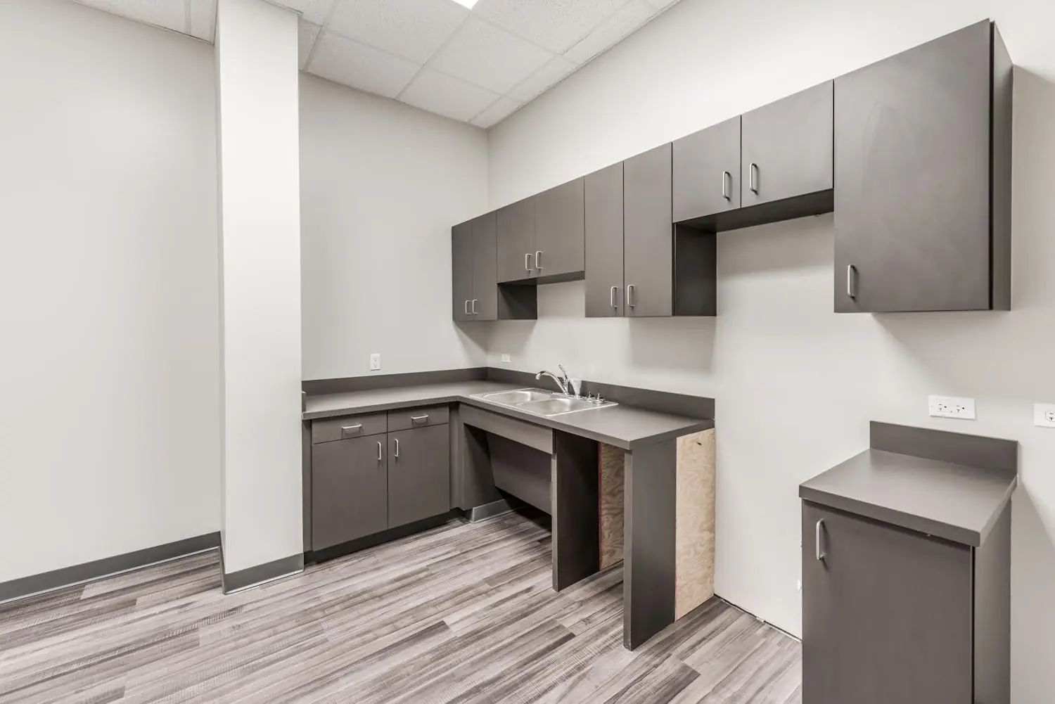 Break room at FSR Services with full-height gray cabinetry, double-basin sink, and laminate counters