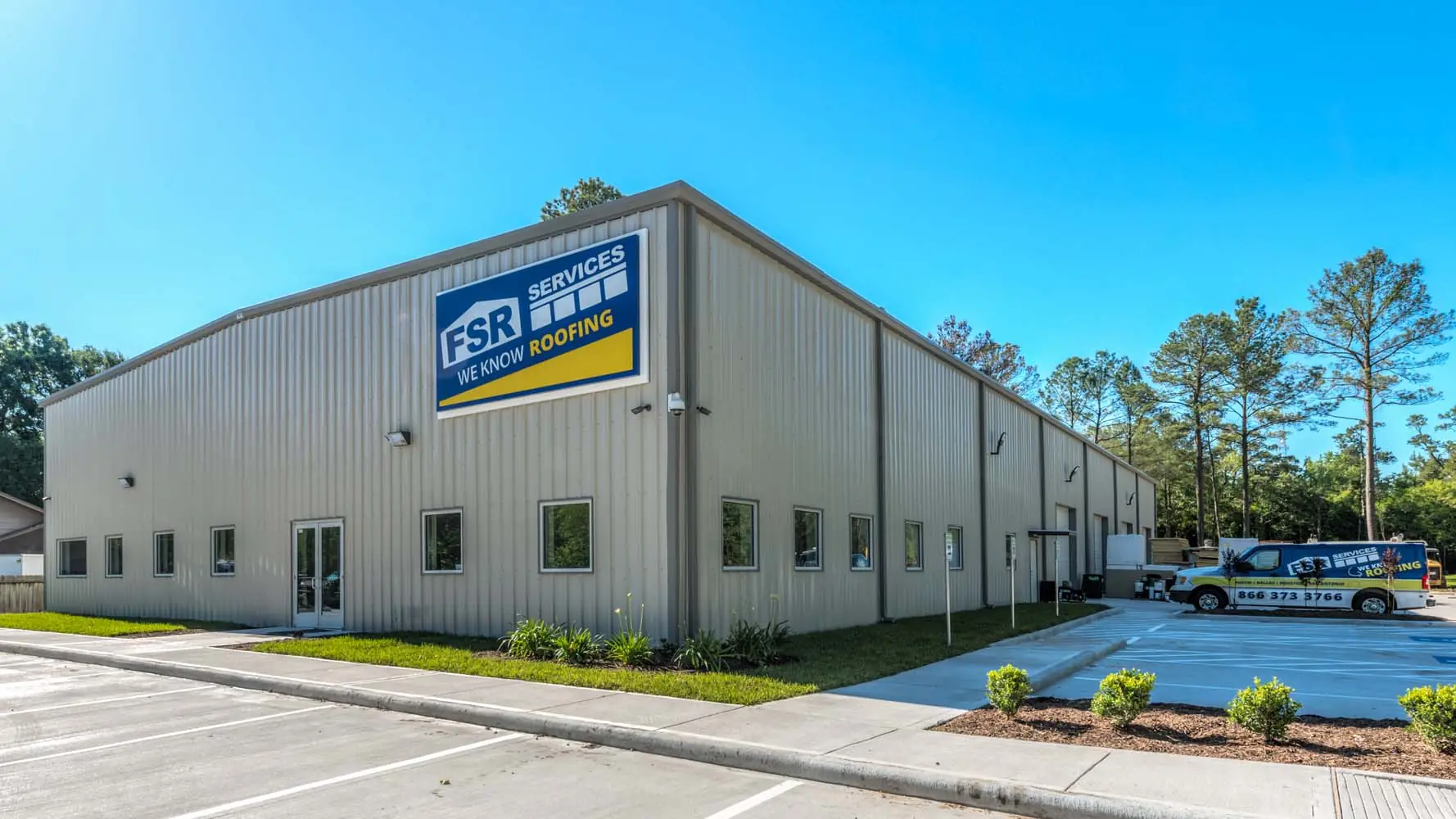 Daytime corner view of the FSR Services headquarters showing the office entry, metal siding, and parking area with branded service van