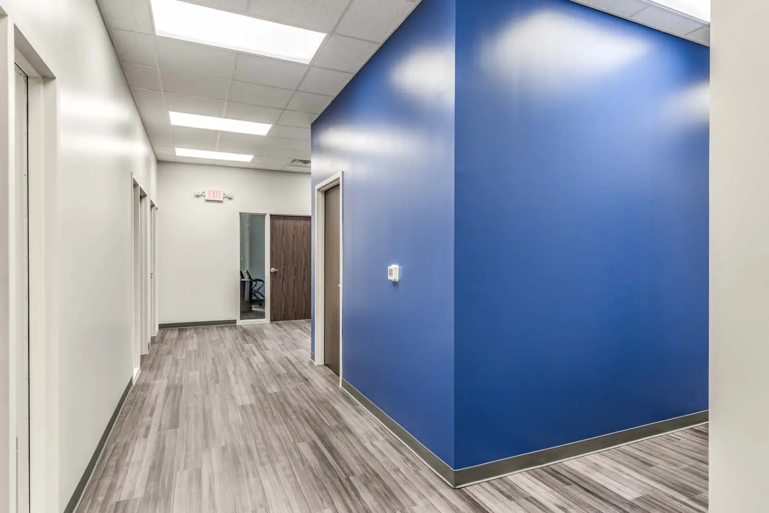 Office corridor at FSR Services with bold blue accent wall and wood-look vinyl plank flooring