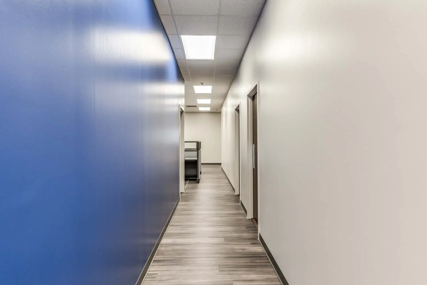 Long interior hallway at FSR Services featuring a blue feature wall meeting white corridor walls