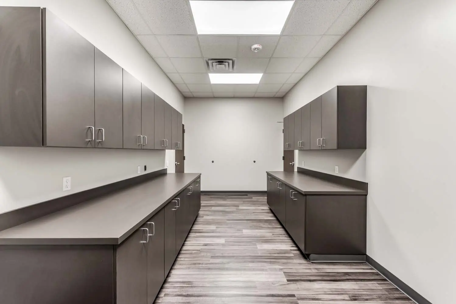 Workroom at FSR Services with full-height gray cabinetry and laminate work counters along both walls
