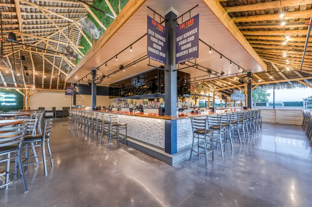 The Yard self-service food and drink counter at LaBrisa with branded banners, bar seating, and pendant lighting
