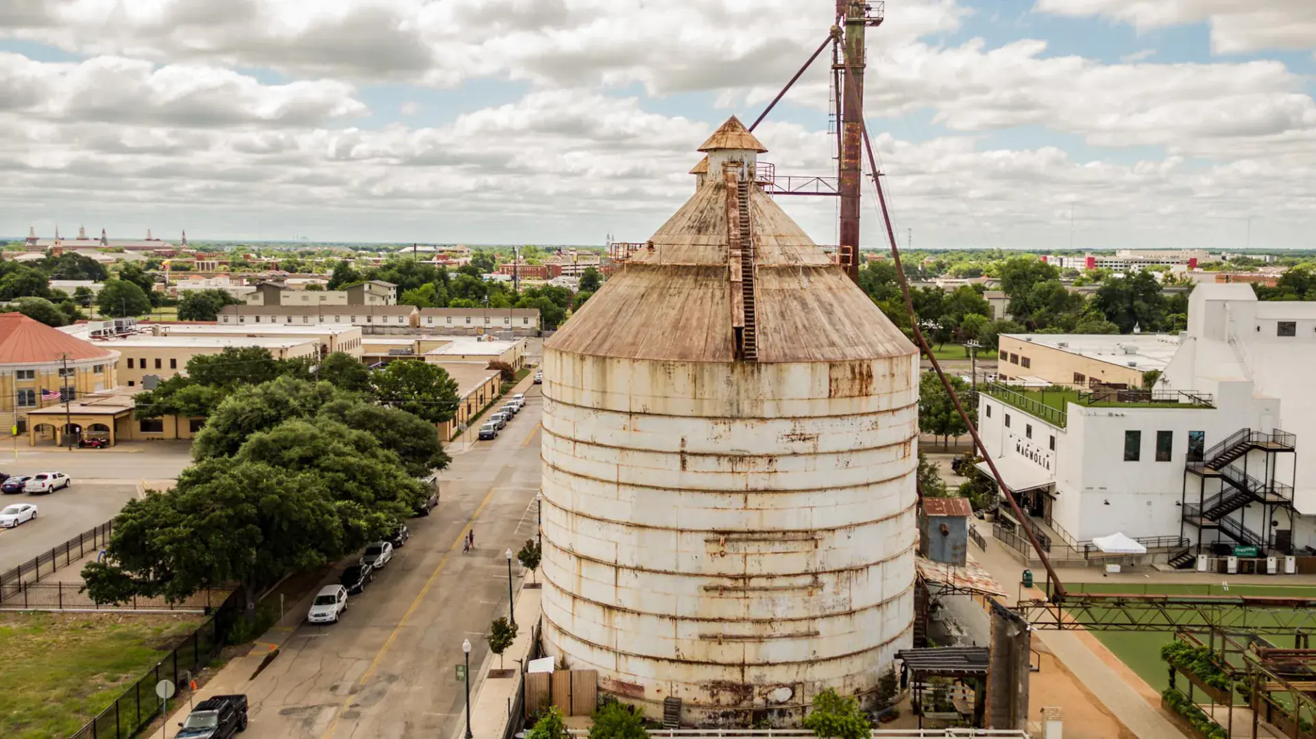 Aerial close-up of the historic cotton oil silos at Magnolia Market in Waco, TX with the white Magnolia warehouse behind