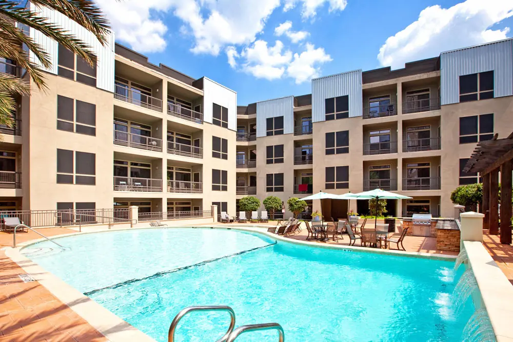 Resort-style courtyard pool at Post Oak Apartments with shaded dining tables and grilling station