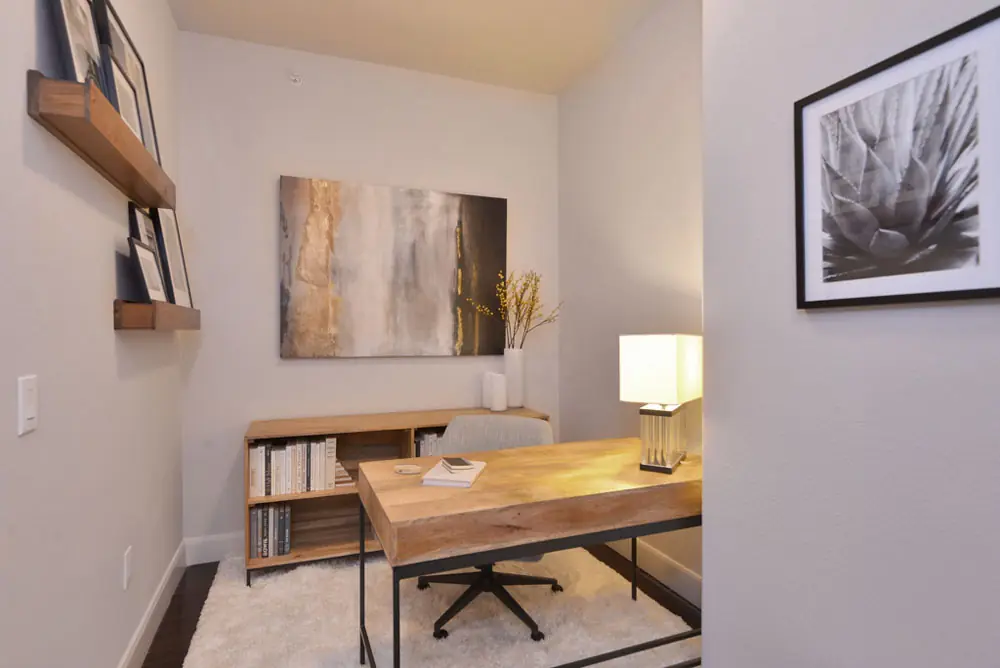 Home office in a Post Oak Apartments unit with wood desk and gallery wall