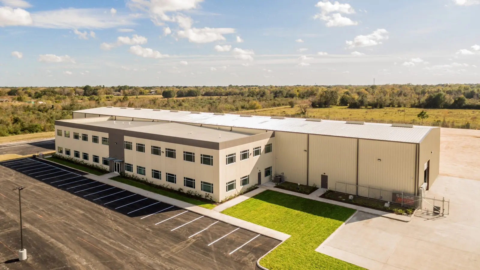 Aerial view of the Repcon Industrial office and warehouse facility in Houston, TX with a two-story office wing attached to a tan metal manufacturing warehouse