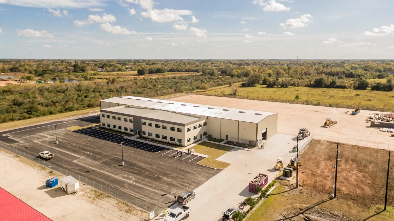 Wider aerial of the Repcon Industrial site showing the office and warehouse building, paved staging yard, and surrounding ranchland near Houston, TX