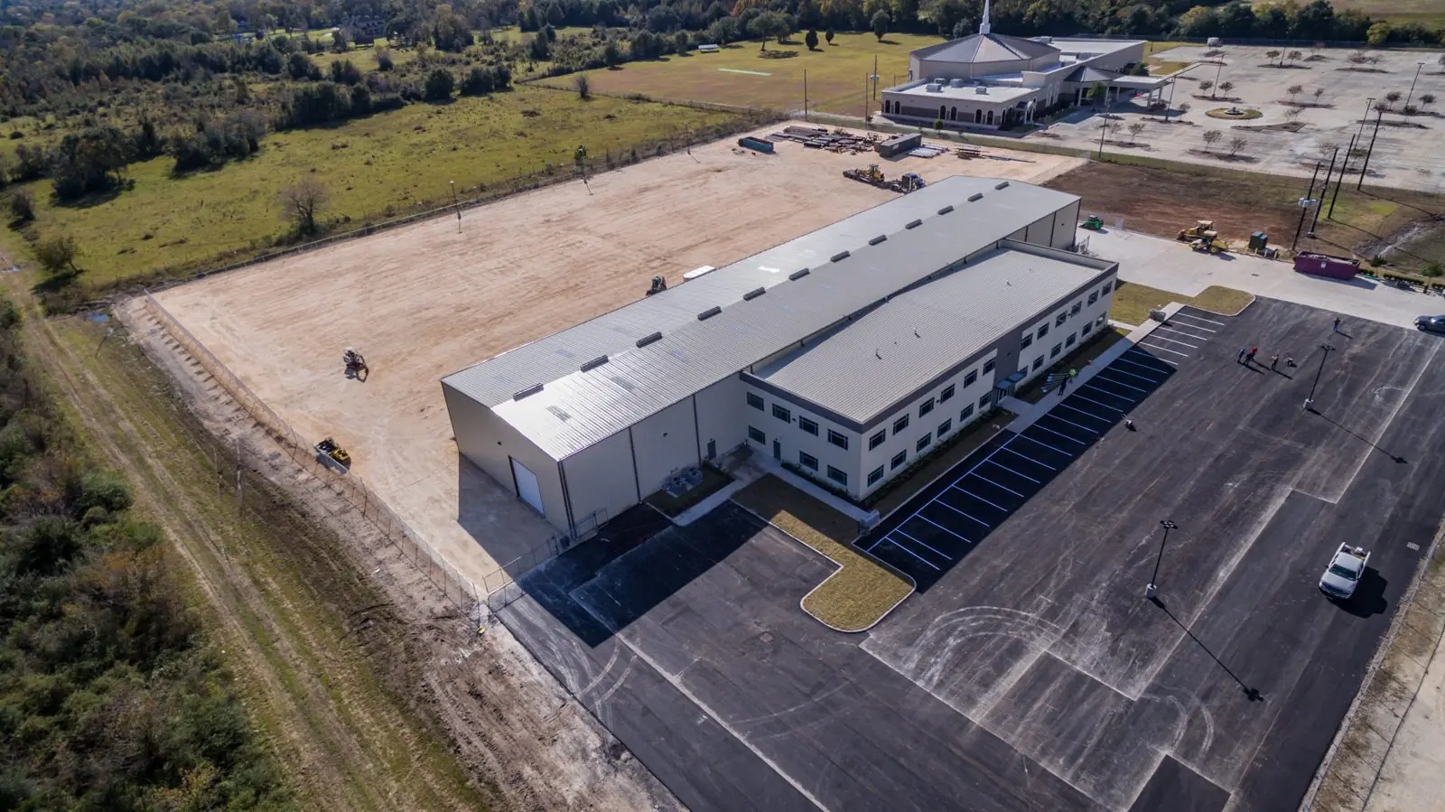 Side aerial of the Repcon Industrial warehouse showing the standing-seam metal roof, large overhead doors, and dedicated office parking field