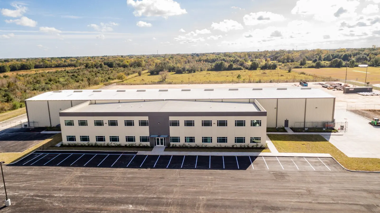 Front elevation of the Repcon Industrial two-story office building in Houston, TX with striped parking lot in the foreground and the warehouse wing behind