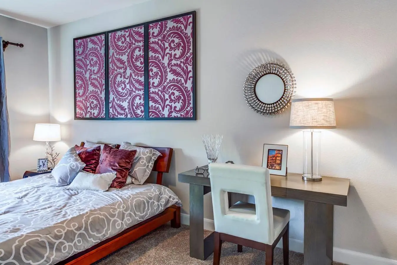 Apartment bedroom at Upper Kirby Apartments staged with a queen bed, framed wall art, and a built-in work-from-home desk area