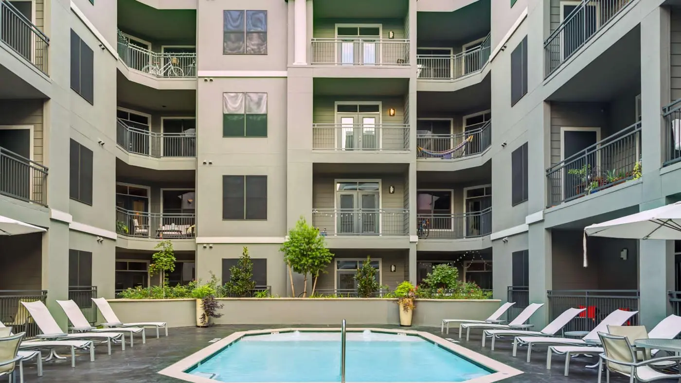 Interior courtyard pool at Westheimer Apartments with lounge chairs and apartment balconies overlooking the deck