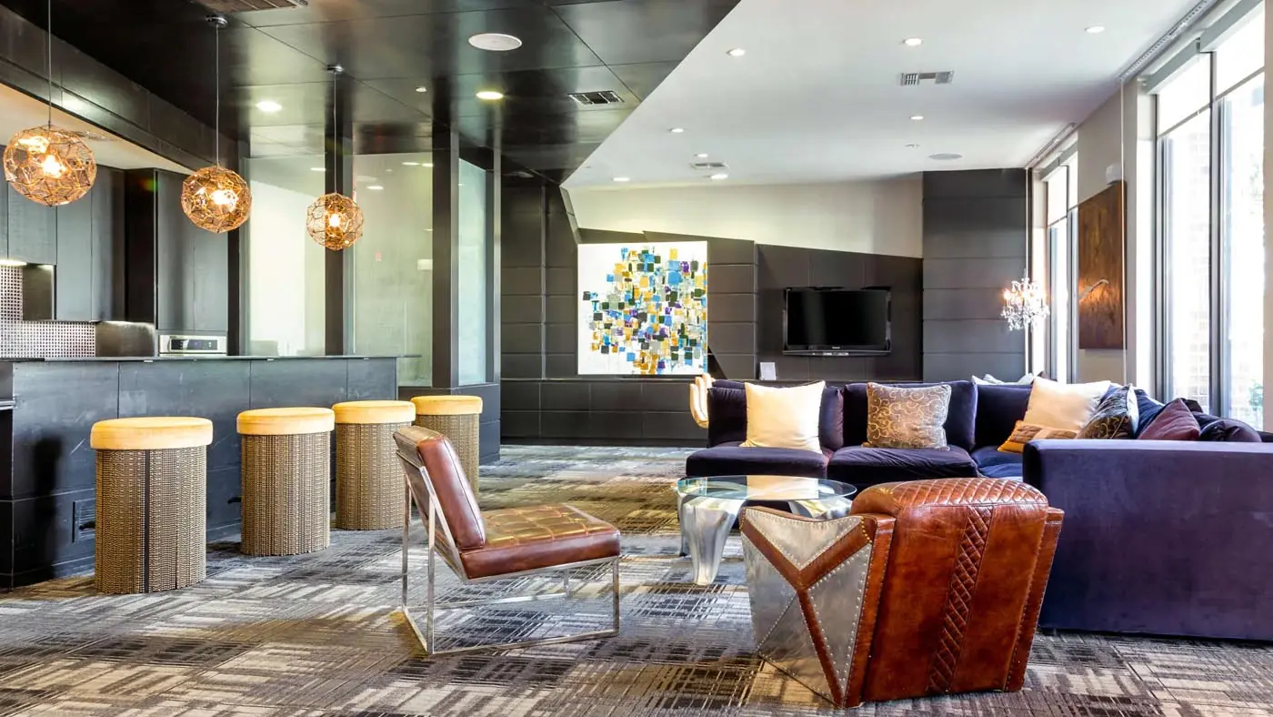 Resident lounge at Westheimer Apartments with pendant lighting, a sectional sofa, and a club-style bar seating area