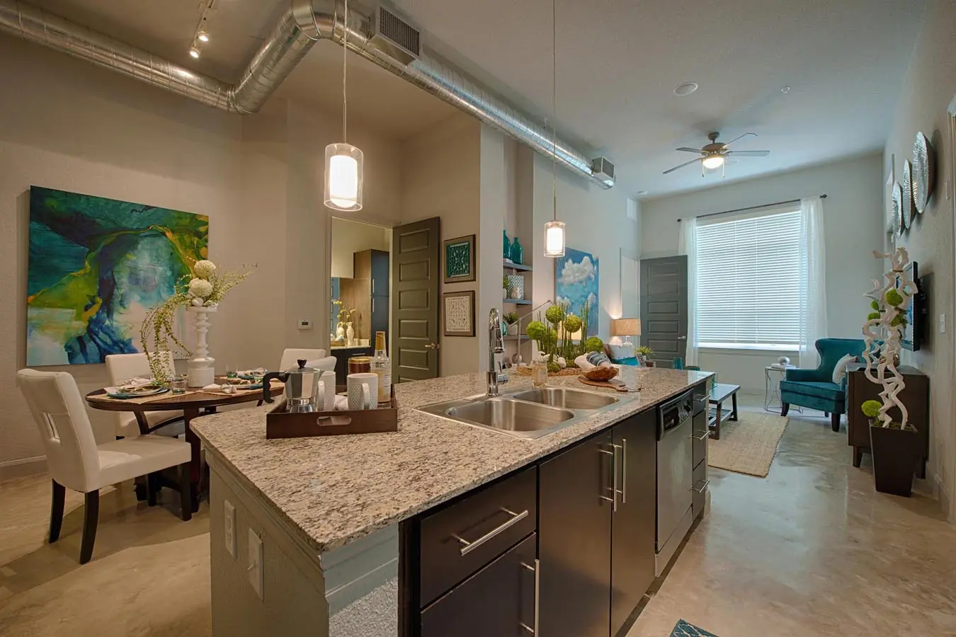 Open-concept apartment interior at Westheimer Apartments with a granite island kitchen, exposed ductwork, and a dining and living area
