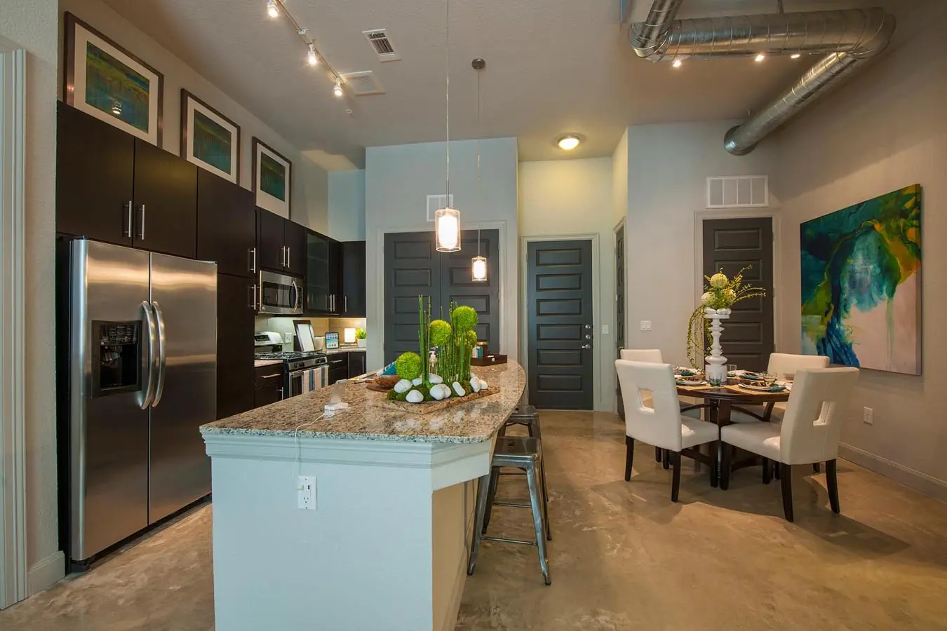 Loft-style apartment kitchen at Westheimer Apartments with stainless steel appliances, granite counters, and high ceilings with exposed ductwork